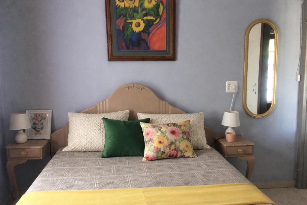 a bedroom with a bed with pillows and a mirror at Cottage 49 in Parys