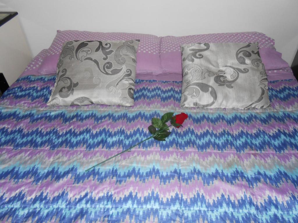 a bed with a colorful bedspread and a flower on it at B&B Appartamenti Napoli in Naples