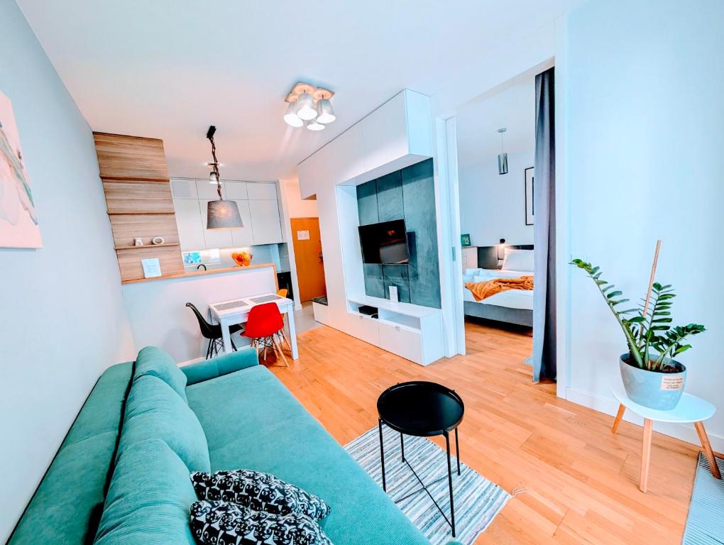 a living room with a green couch and a bedroom at Kolejowa ApartHotel in Warsaw