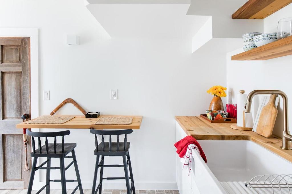 a kitchen with a sink and two bar stools at The Forest Door - Studio Suite in Stone Cottage in Tryon
