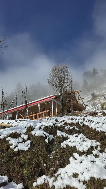 a house on top of a snow covered hill at The magic meadows in Kulu