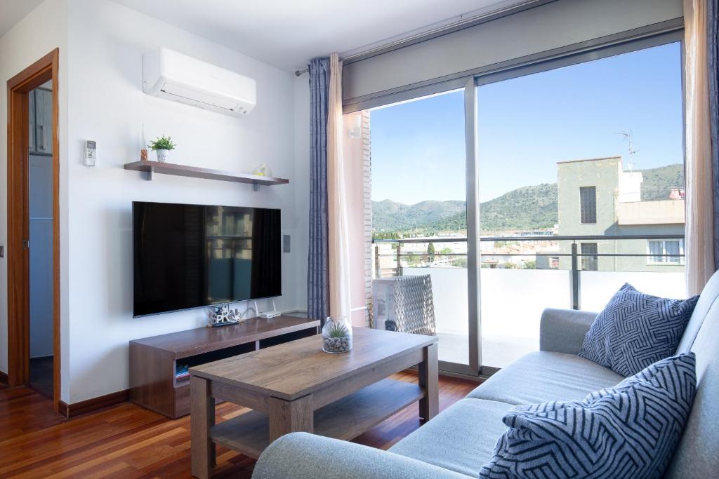 a living room with a couch and a tv at Les nid doré suites in Roses
