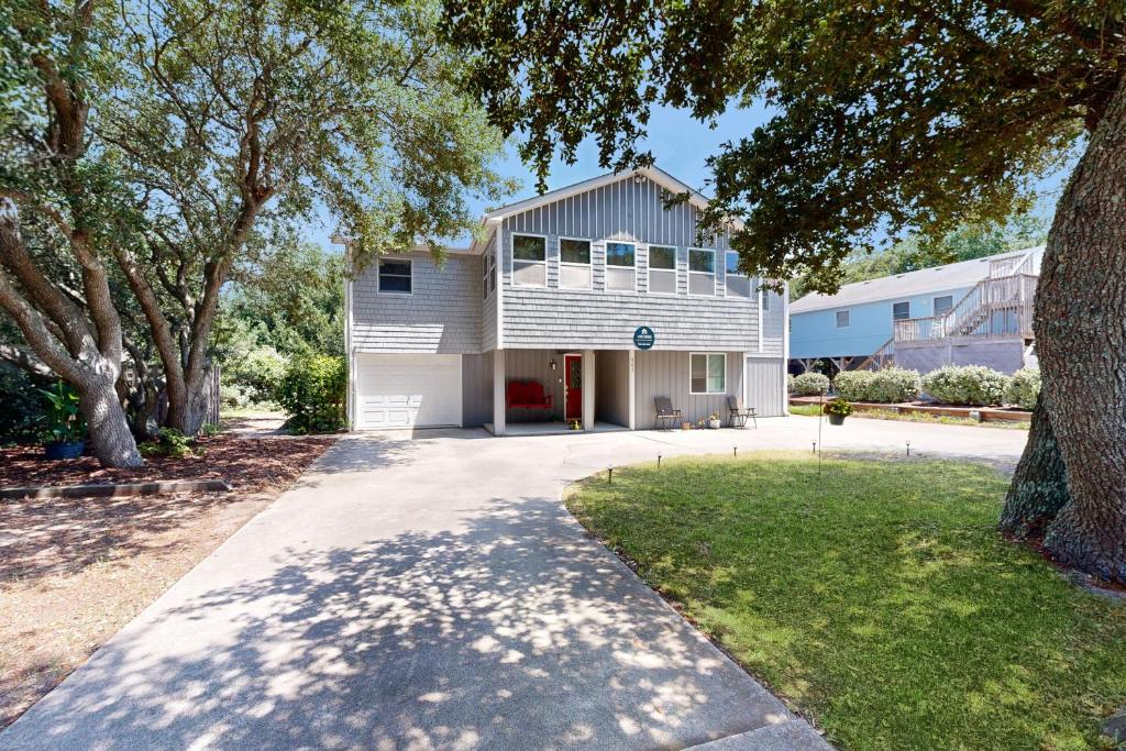 a white house with a tree and a driveway at Worries not Found in Kill Devil Hills