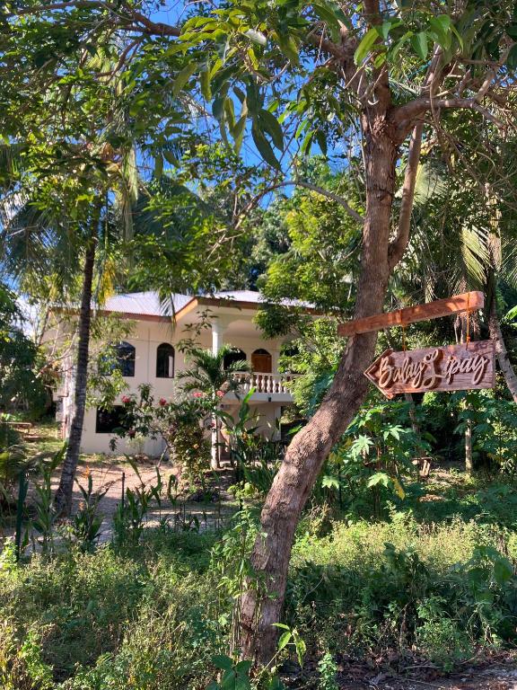 a sign on a tree in front of a house at Balay Lipay - Spacious Private House in Siquijor in Siquijor