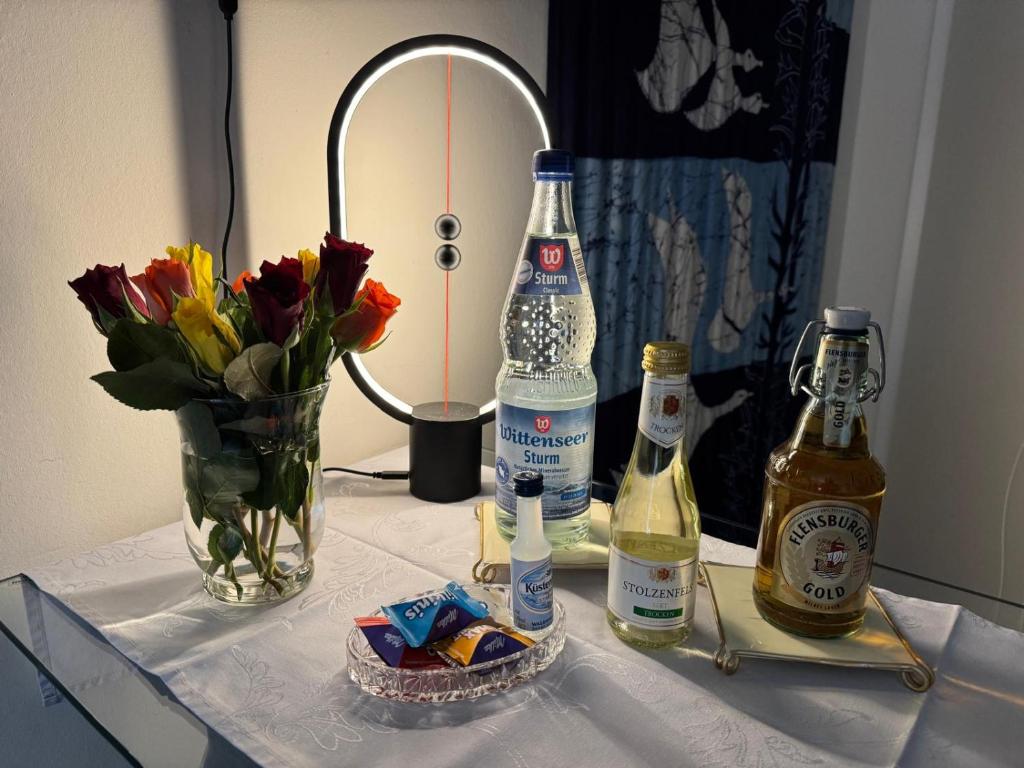 a table with two bottles of alcohol and a vase of flowers at Gode Wind in Eckernförde