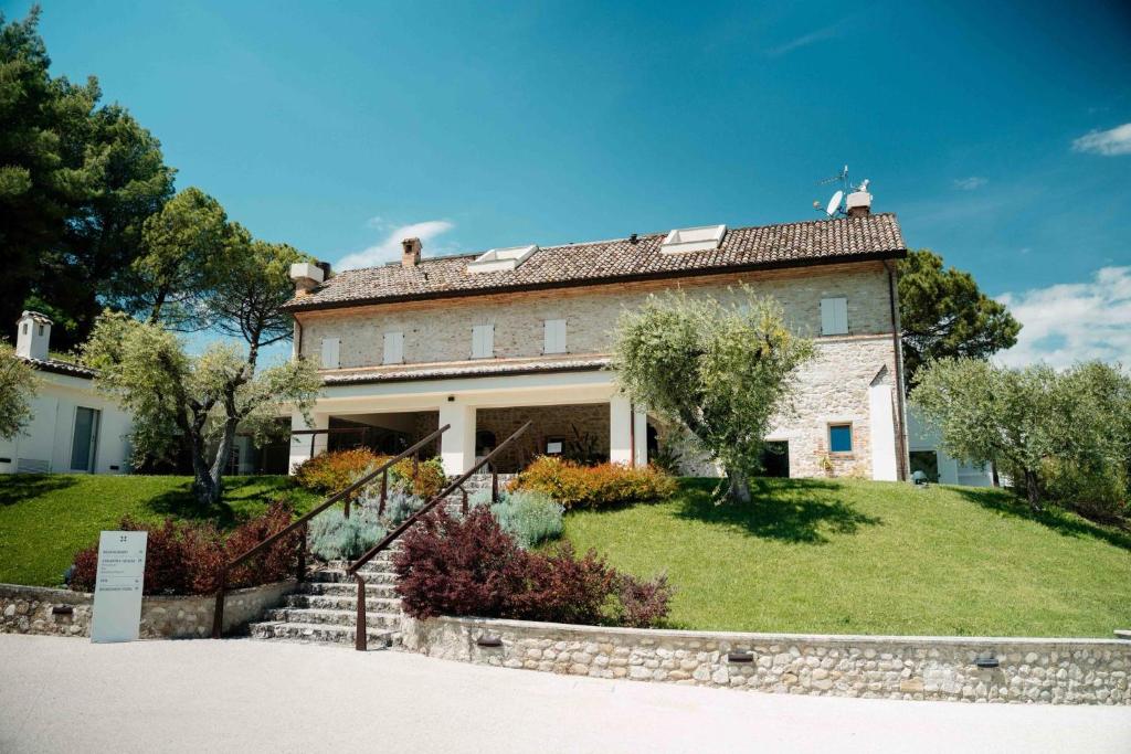 an old house on a grassy hill with trees at Colle Serrano Relais & SPA in Ripatransone