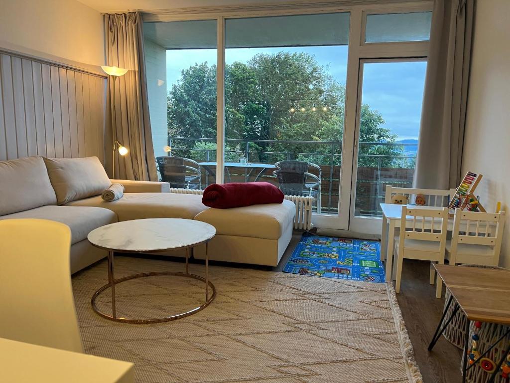 a living room with a couch and a large window at Familienfreundliche Ferienwohnung Bayerischer Wald mit Pool in Freyung