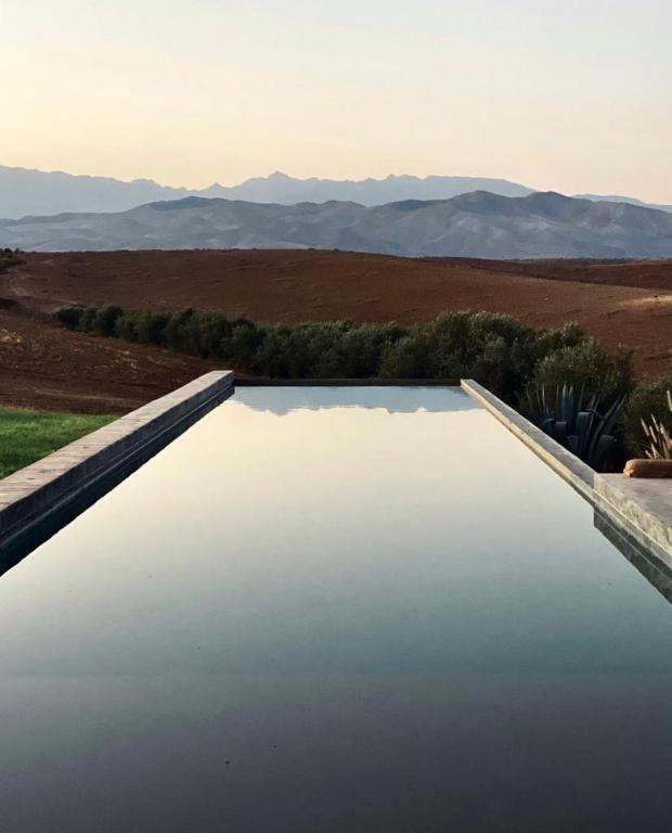 a pool of water in a field with mountains in the background at Villa K by Studio KO - Private Luxury Estate Marrakech in Marrakesh