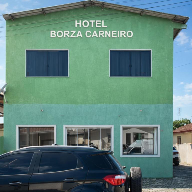 a green building with a car parked in front of it at Hotel Borza Carneiro in Piraí do Sul