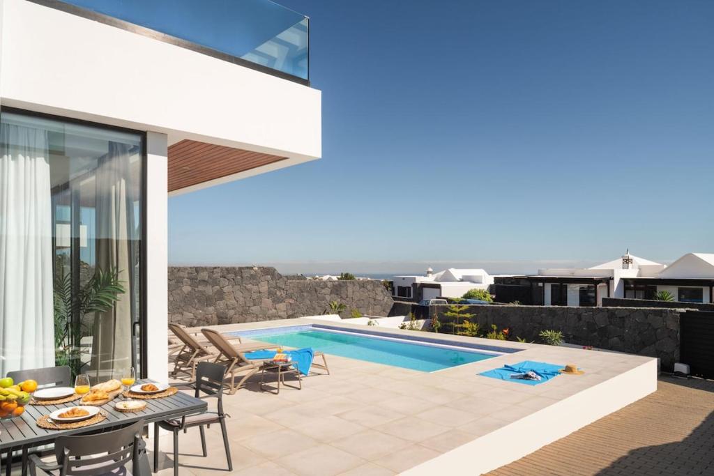 a patio with a table and a swimming pool at OCEANIQUE by Buenavilla in Tías