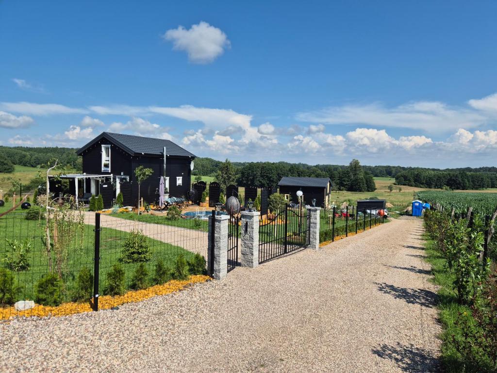 a fence in front of a house in a field at Domek Dolina Żurawia in Borzynowo