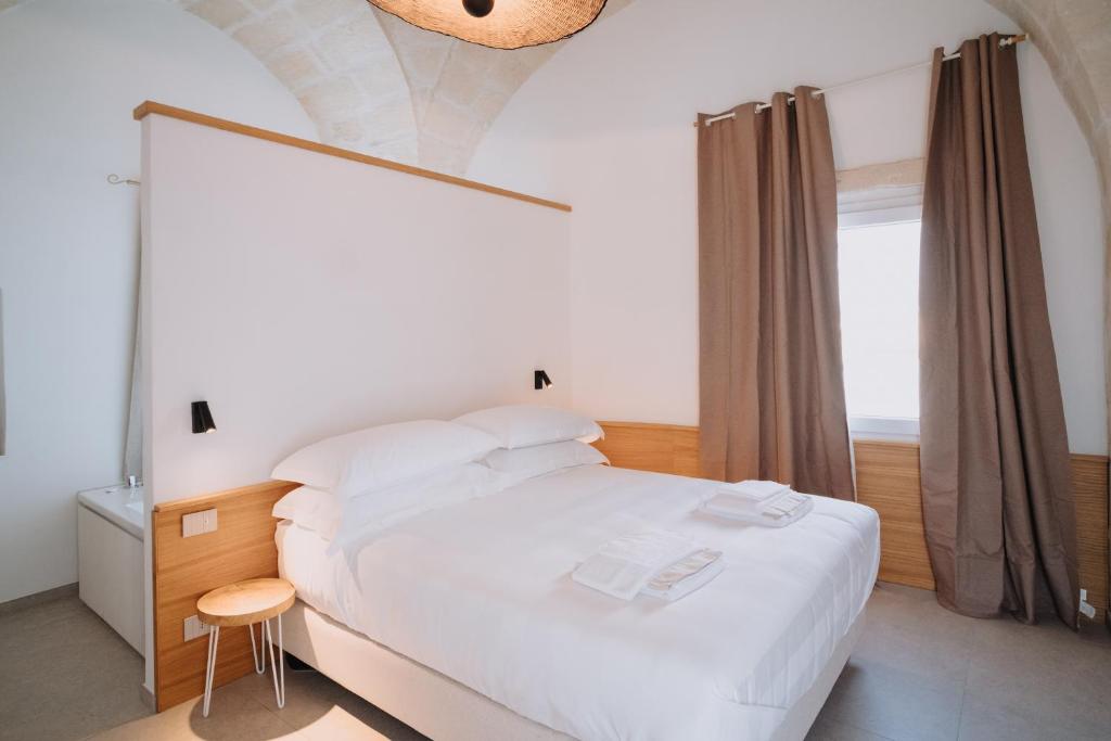 a bedroom with a large white bed and a window at Cavae - Le stanze in Massafra