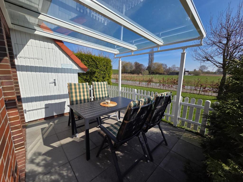 a patio with a table and chairs and a fence at Ferienhaus Seemöwe mit Deichblick Butjadingen-Burhave in Burhave