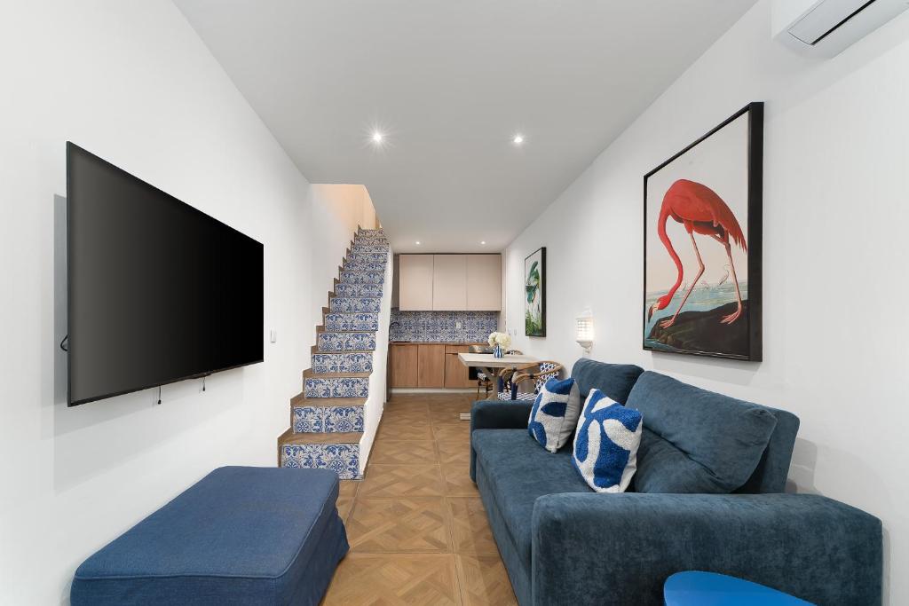 a living room with a blue couch and a flat screen tv at Casa Margot Old Town Rooftop Walk Promenade in Portimão