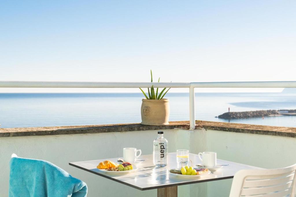 a table with two plates of food and a view of the ocean at Blanca by Uephotels in Can Picafort