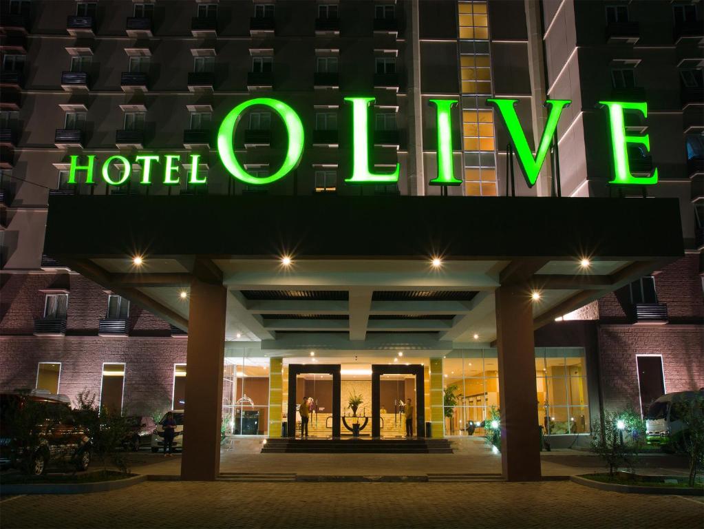 a hotel entrance with a green neon sign on it at Hotel Olive in Tangerang