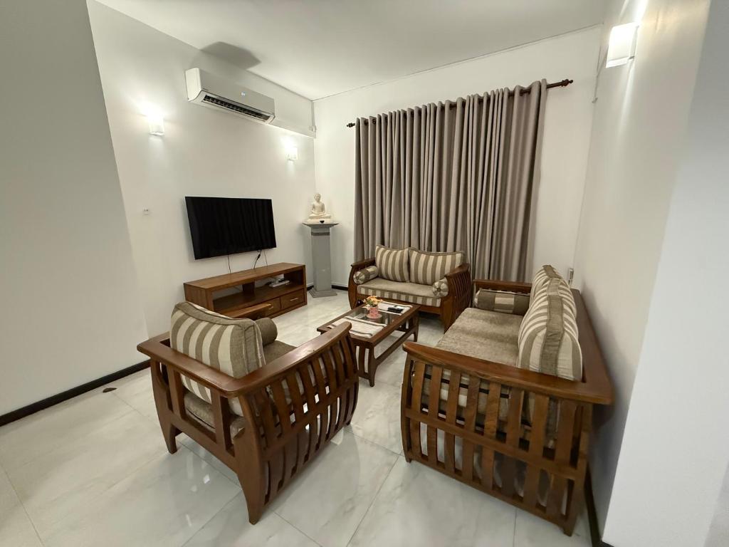 a living room with a couch and chairs and a television at Lucky Homes in Maharagama