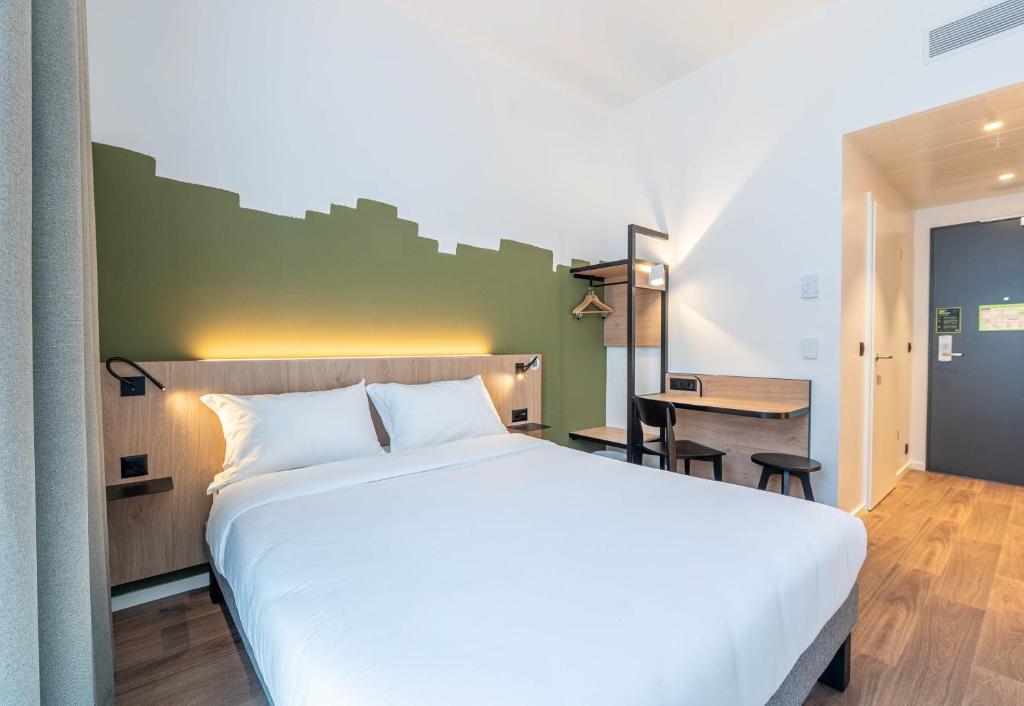 a bedroom with a large white bed and a desk at B&B HOTEL Geneva Airport in Geneva