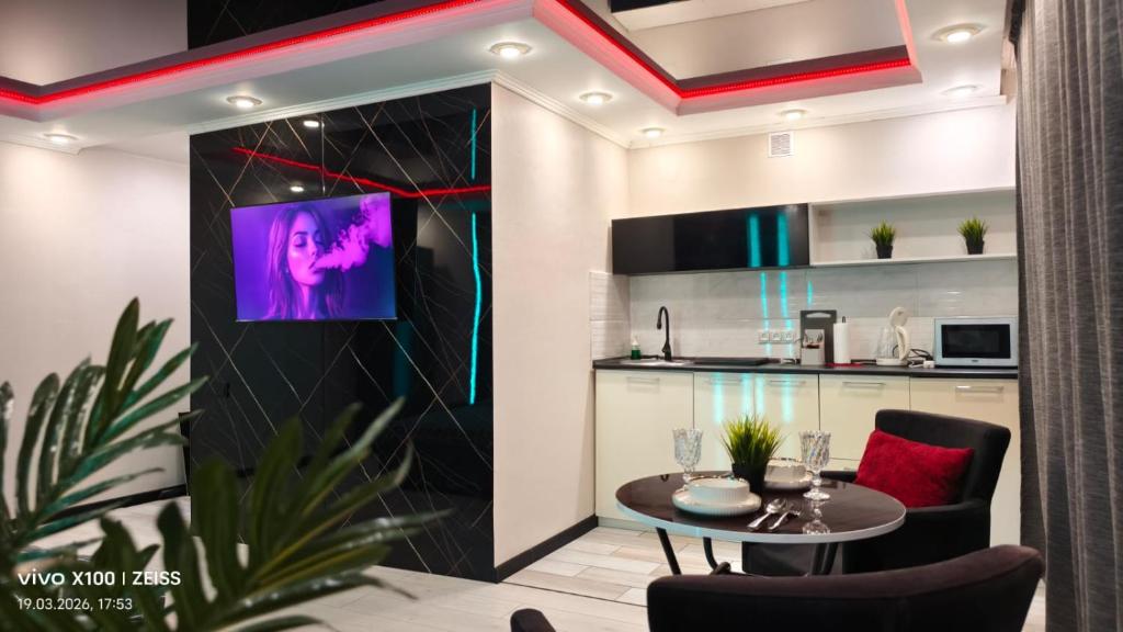 a living room with a table and a kitchen at Астана 34 in Ustʼ-Kamenogorsk