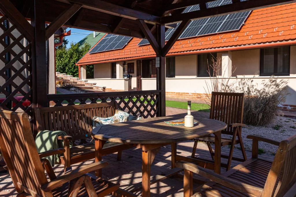 a wooden table and chairs on a patio with solar panels at Bakonyi Múzsa Vendégház in Bakonyszentlászló