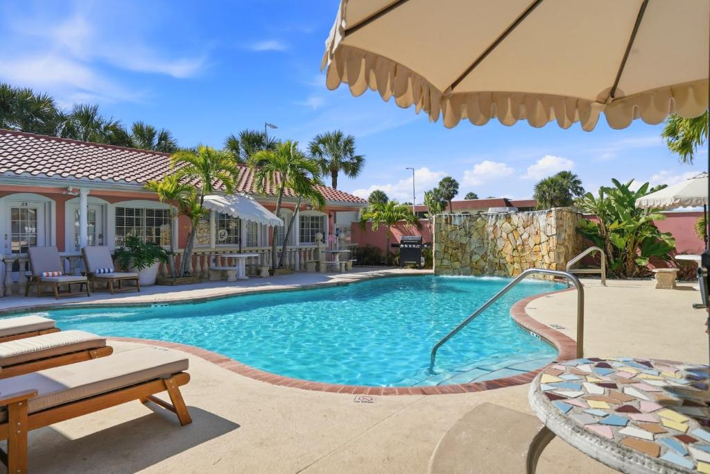 a swimming pool with a patio furniture and an umbrella at Blind Pass Resort Motel in St. Pete Beach