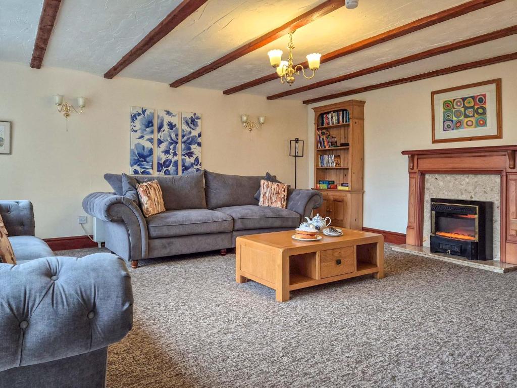 a living room with a couch and a fireplace at Whortleberry Cottage in Wheddon Cross