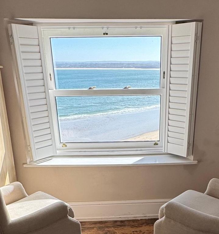 a window in a room with a view of the ocean at Minster Panorama & Minster Vista - - UNBROKEN BEACHFRONT VIEWS - - TWO STUNNING GEORGIAN HOUSES THAT CONNECT - - PRIVATE PARKING - - Beautifully Refurbished MARCH 2026 in St Ives
