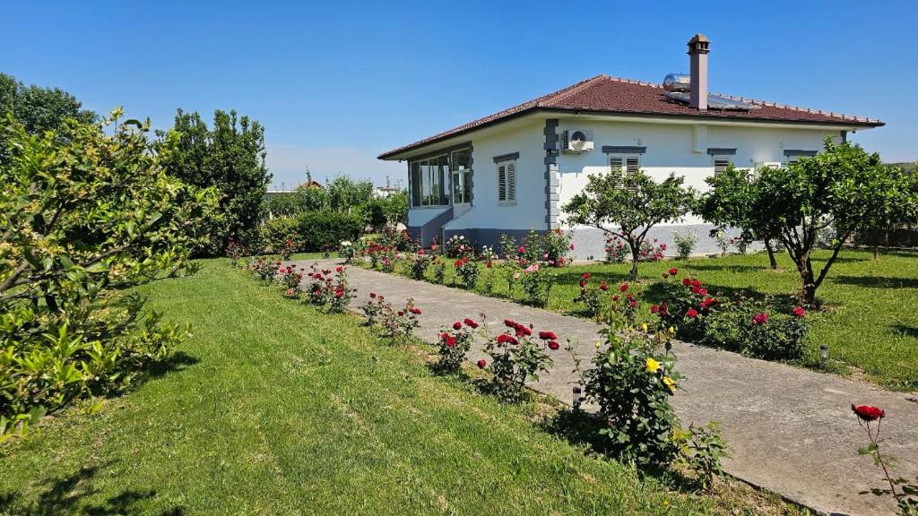 a house with a garden of flowers in front of it at Vila Rrozhani in Mabë