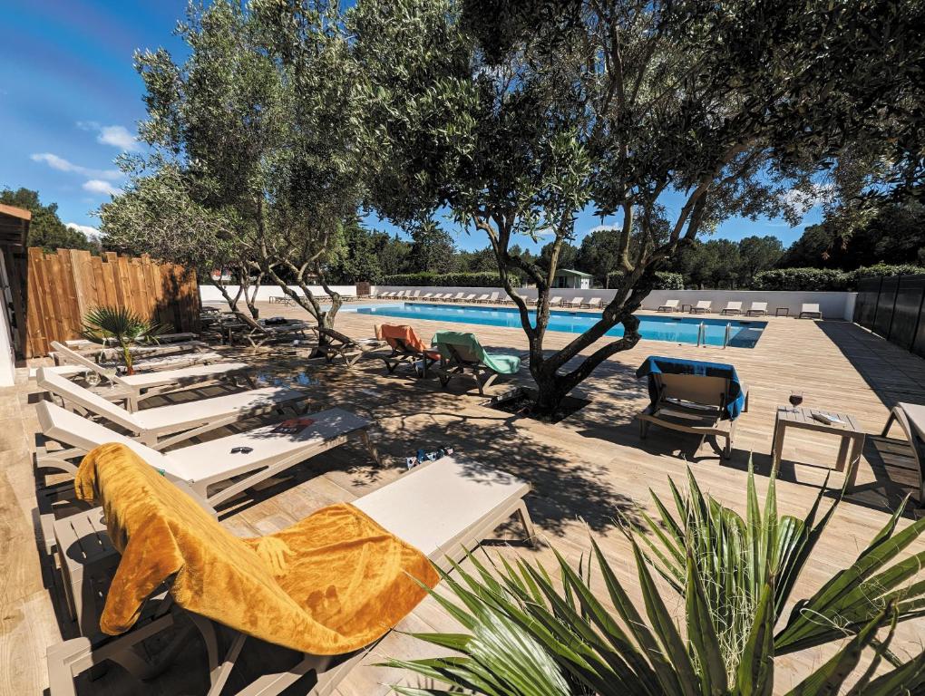 a pool with chaise lounge chairs and a swimming pool at VTF Village de vacances Le Domaine d'Agde in Agde