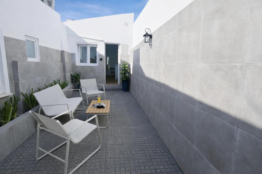 a patio with chairs and a table and a wall at Cascais Garden House 105 in Cascais
