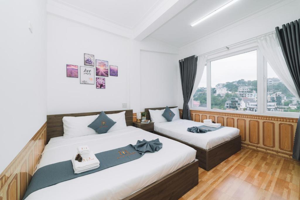 a bedroom with two beds and a large window at AN TÂM House Đà Lạt in Da Lat