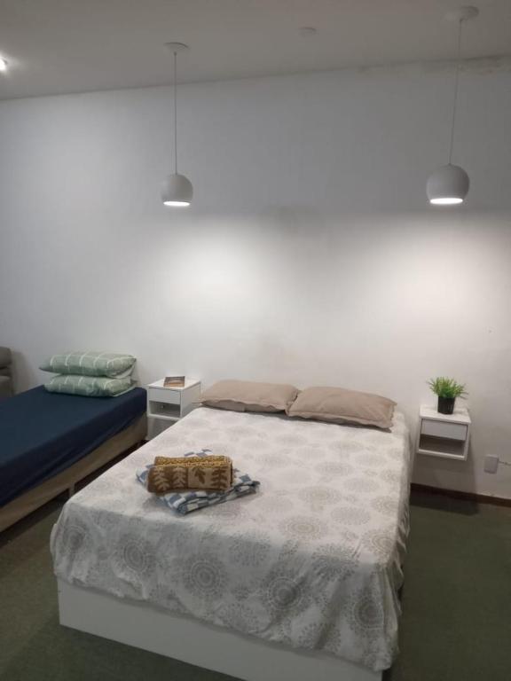 a bedroom with a bed with a white bedspread and two tables at Apto Candelária in Rio de Janeiro