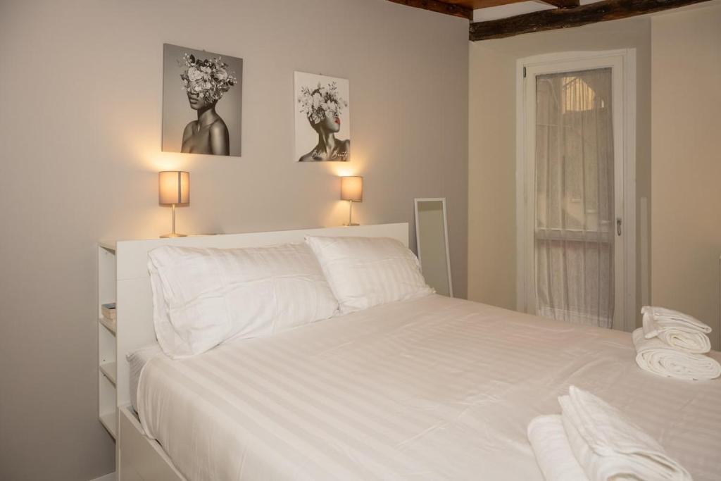 a white bed in a bedroom with two pictures on the wall at Ledy Apartment in Lovere