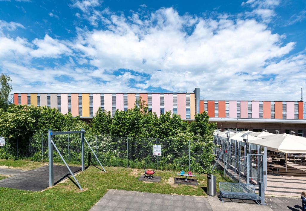 une aire de jeux devant un grand bâtiment dans l'établissement B&B HOTEL Lully 3 Lakes, à Estavayer-le-Lac