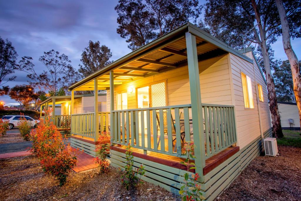 a tiny house with a porch with lights on it at Albury Gardens Tourist Park in Lavington