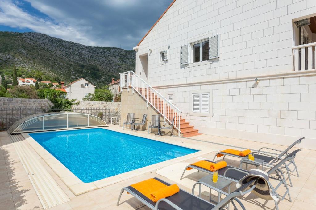 a swimming pool with chairs and a house at Villa Florence - Mediterranean GardenPool in Zaton