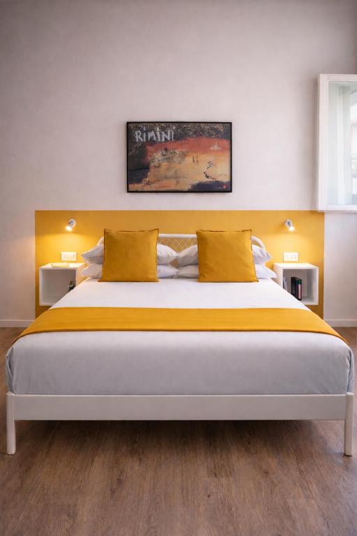 a bedroom with a large bed with yellow pillows at Suite Apartments - Corso51 in Rimini