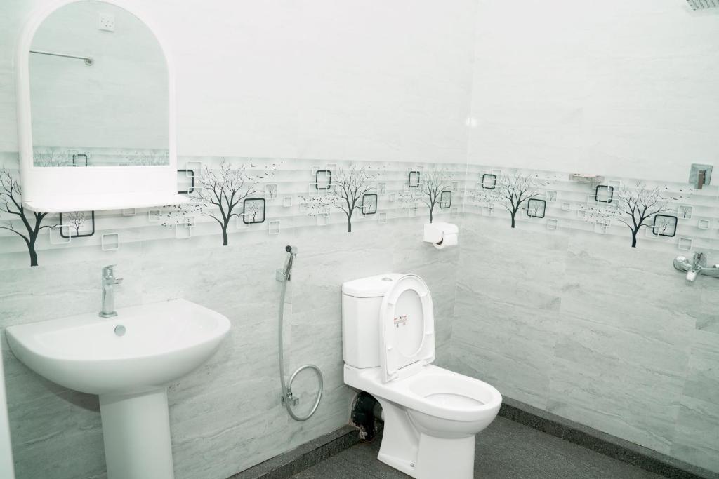 a bathroom with a sink and a toilet and a mirror at G K Guest House in Kalkudah