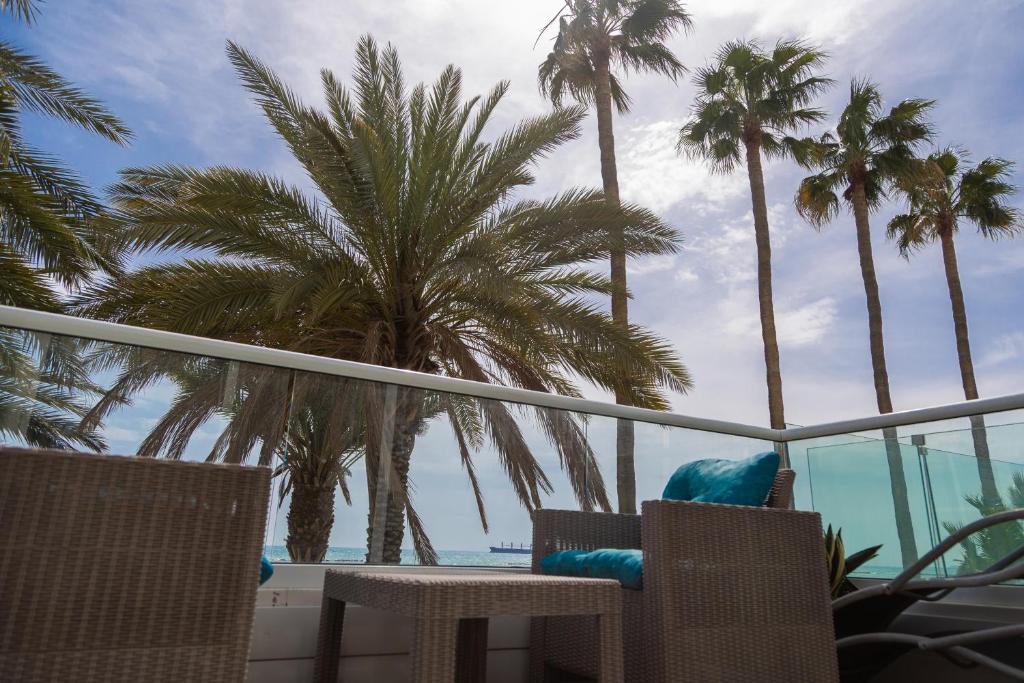 a balcony with palm trees and a view of the ocean at Nautica Luxe Beachfront in Oroklini