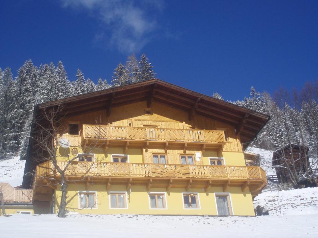 a yellow building with a wooden roof in the snow at Grasreithof in Grossarl