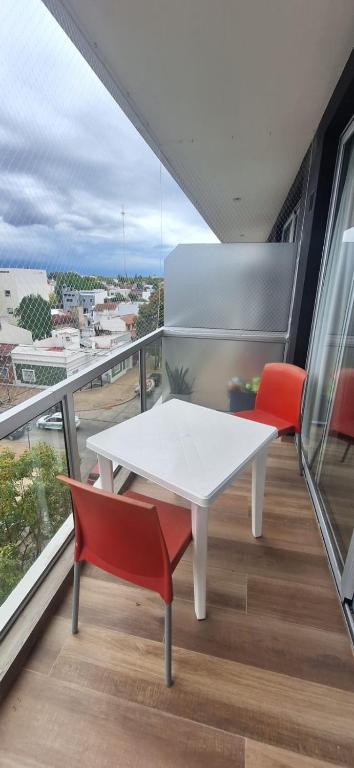 a white table and two red chairs on a balcony at La Raquel in La Plata