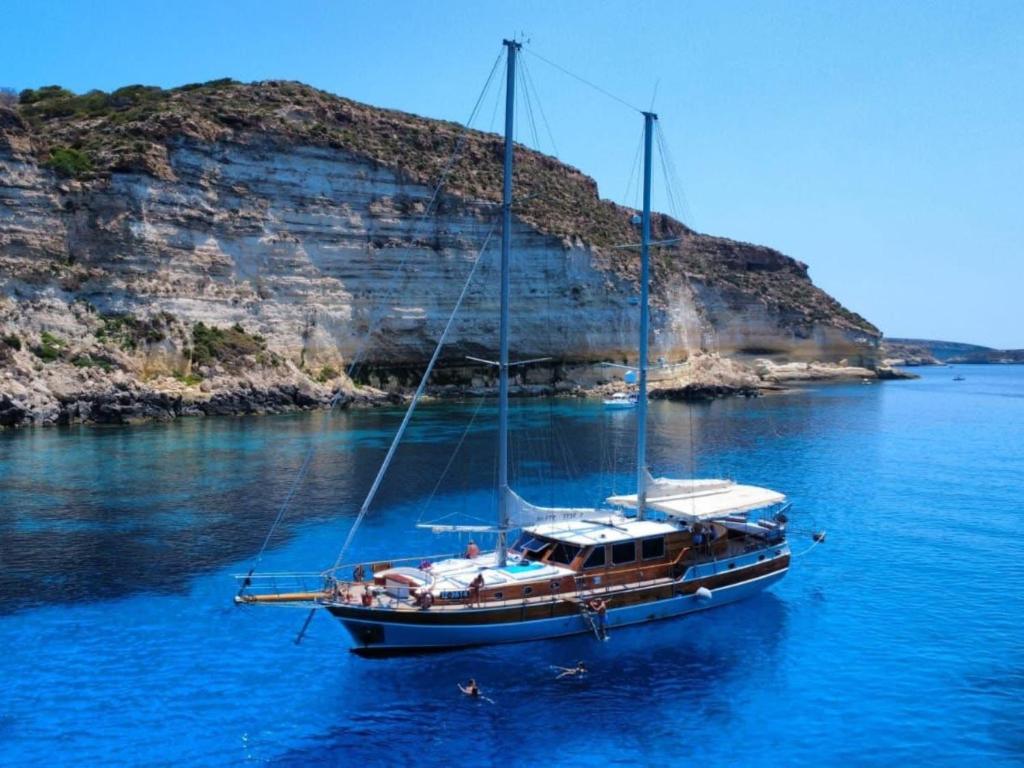a boat in the water next to an island at Caicco Silver Star 2 by Blue Marine in Lampedusa
