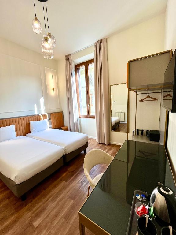a hotel room with two beds and a desk at Hotel Duca D'Aosta in Florence