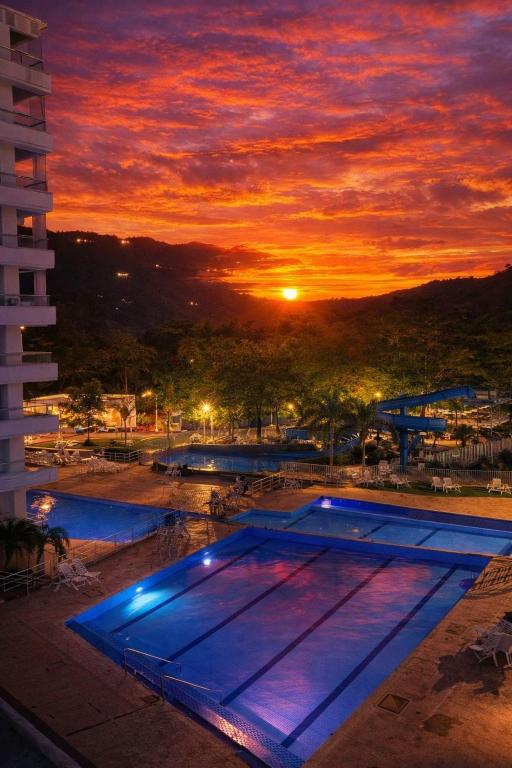 a swimming pool with a sunset in the background at Hermoso Apartasol San Jeronimo in San Jerónimo