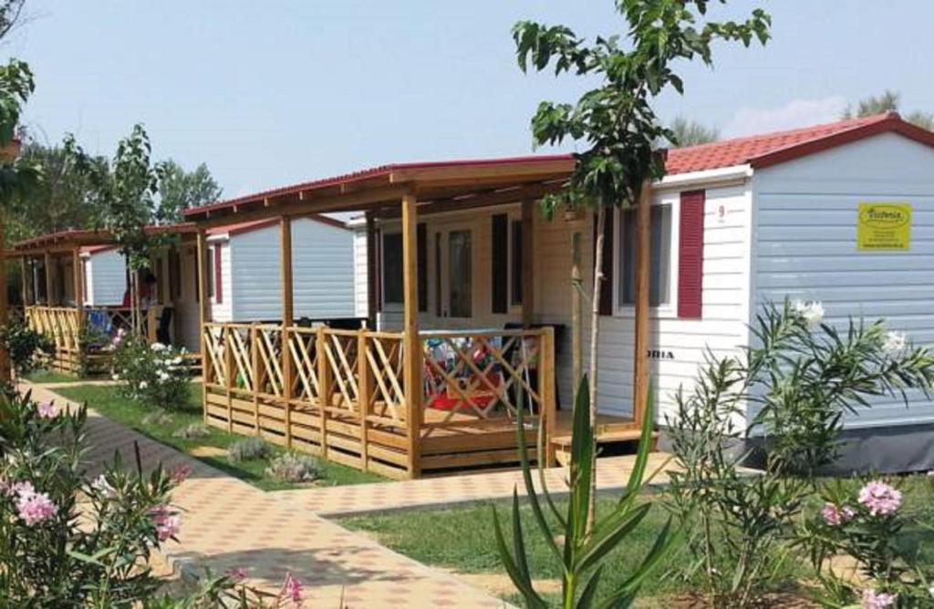 ein kleines weißes Haus mit einer Veranda und einer Terrasse in der Unterkunft Mobile Homes Victoria San Marino in Lopar