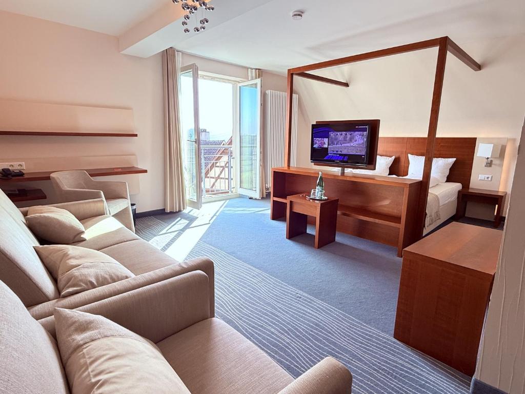 a hotel room with a couch and a bed and a television at Krone Langenburg by Ammesso in Langenburg