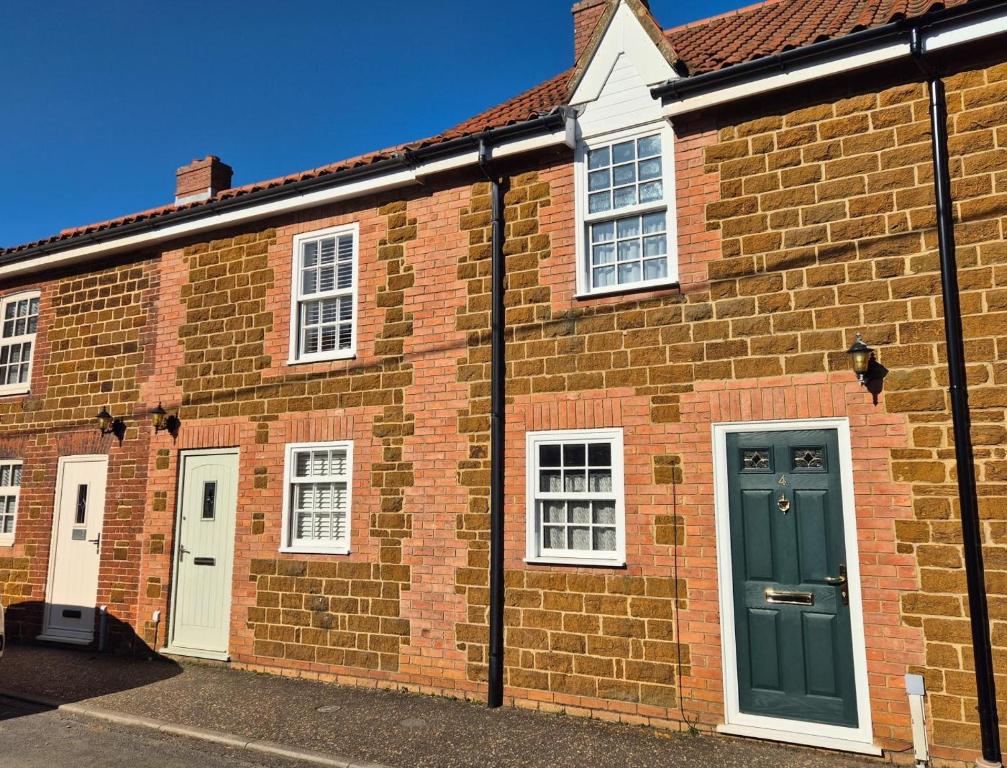 a brick building with white windows and a green door at 2 Bed in Snettisham oc-d31668 in Snettisham