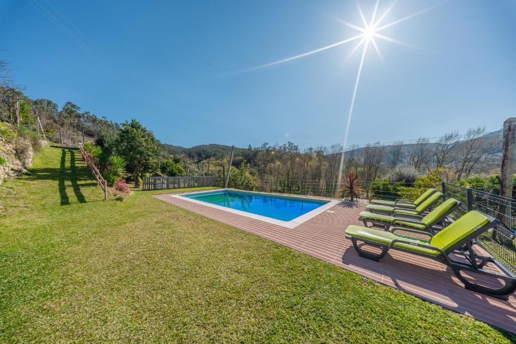 a group of lawn chairs next to a swimming pool at Casa da Portazinha - by Proguest in Amares
