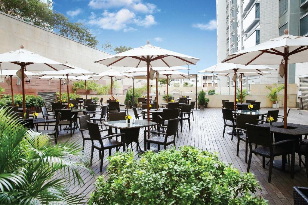 un ristorante con tavoli, sedie e ombrelloni di Harbour Plaza 8 Degrees a Hong Kong