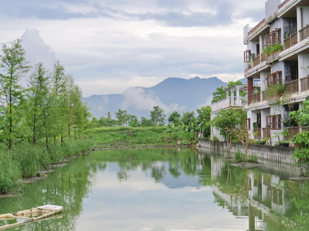 a river between two buildings with mountains in the background at Beautiful Yilan Resort in Dongshan